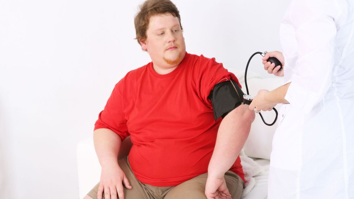 Doctor examining  patient obesity on light background