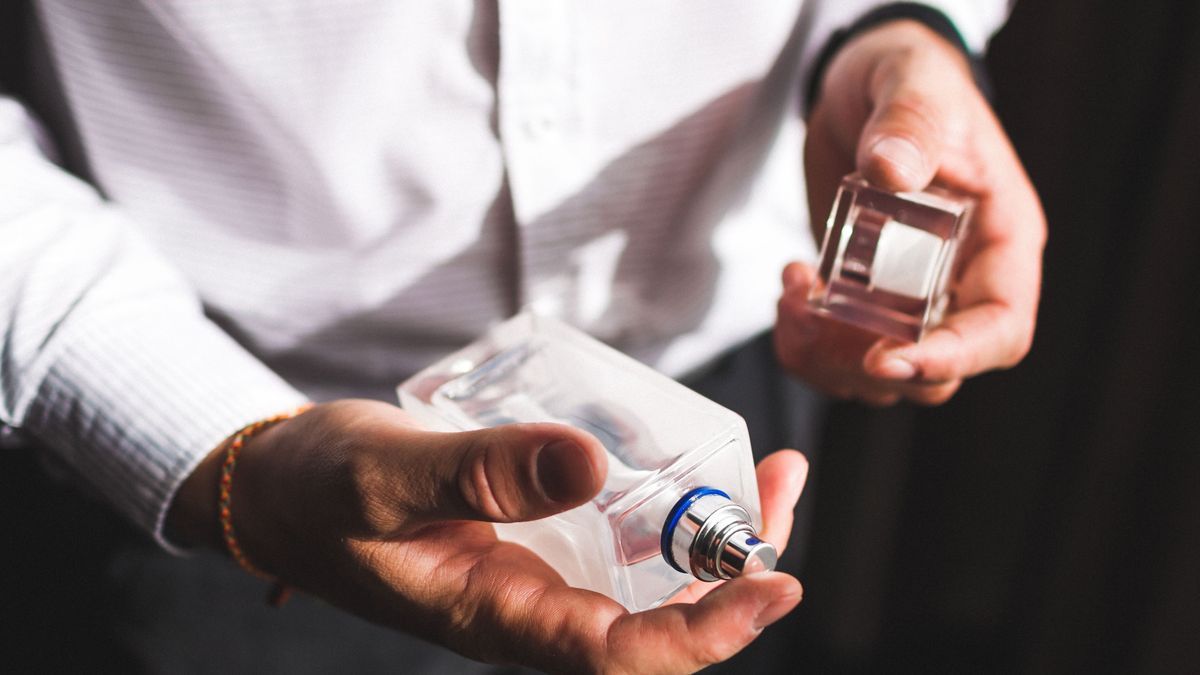 Man holding bottle of perfume and smells fragrance