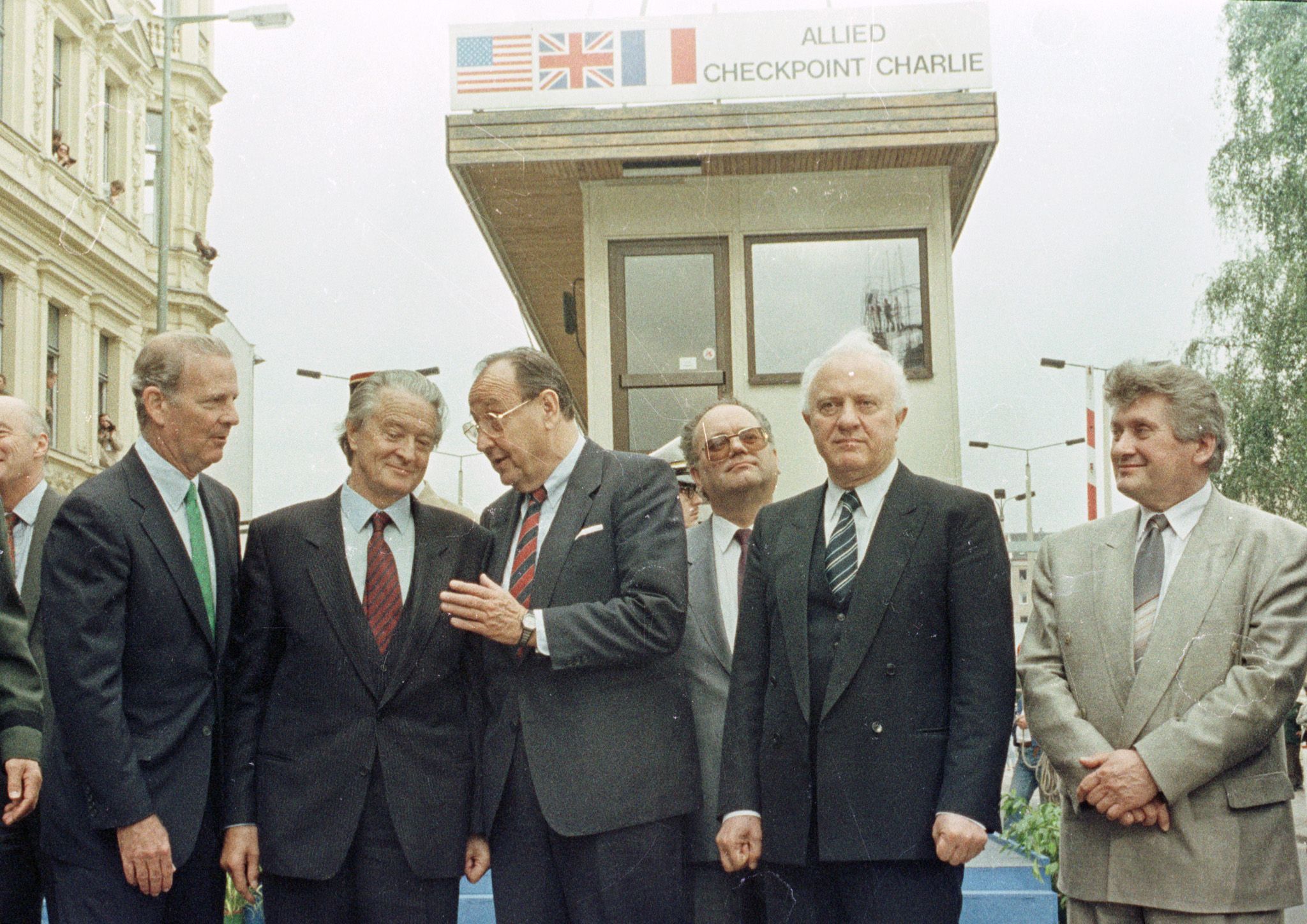 Der französische Außenminister Roland Dumas, der westdeutsche Außenminister Hans Dietrich Genscher, der sowjetische Außenminister Eduard Schewardnadse und der Ostberliner Bürgermeister Tino Schwierzina (v.l.n.r.) stehen am 22. Juni 1990 vor der gehobenen alliierten Einrichtung, als jene vom Checkpoint Charlie in Berlin entfernt wurde.