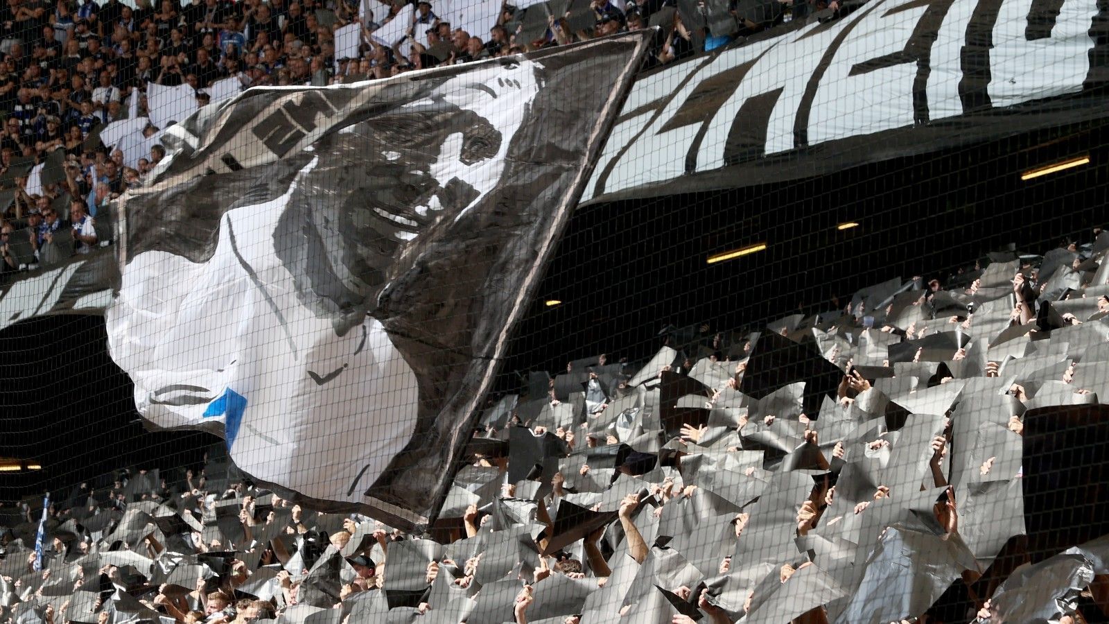 
                <strong>Erinnerung in der Kurve</strong><br>
                In der HSV-Kurve, die vor dem Spiel eine ganz in Trauerfarben gehaltene Erinnerungs-Choreo enthüllt, wird eine Fahne mit dem Gesicht der Vereinslegende geschwenkt. 
              