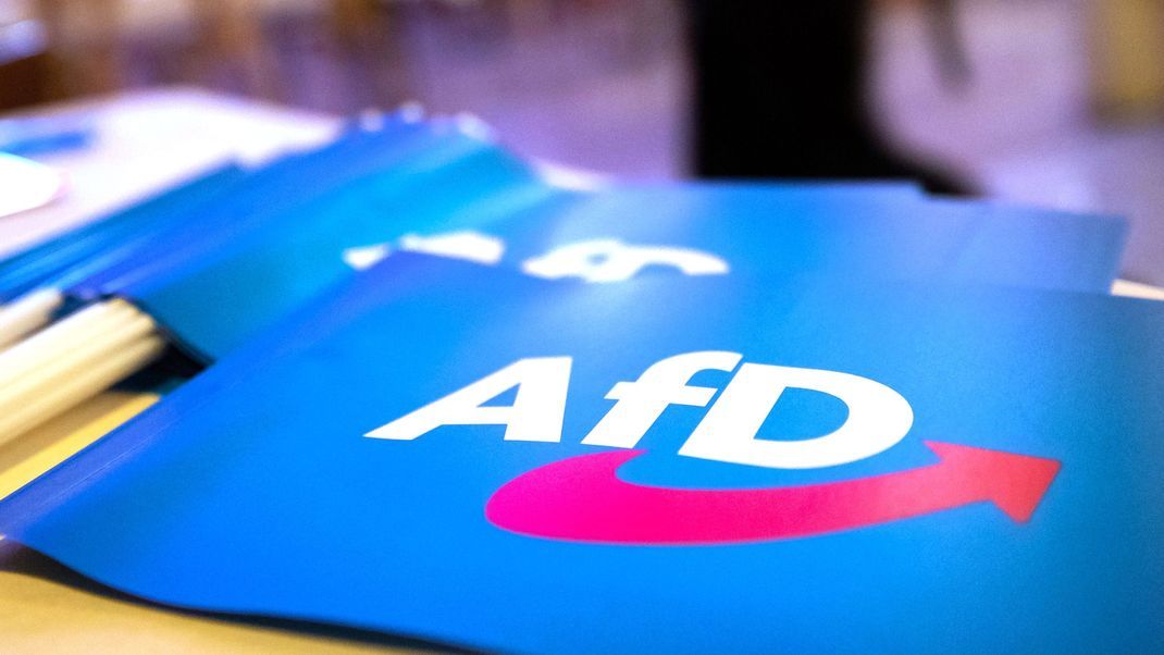 Fähnchen mit dem Logo der AfD liegen beim Landesparteitag der AfD Bayern auf einem Tisch.