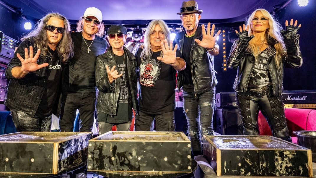 1. August 2024, Schleswig-Holstein, Wacken: Die Scorpions und Metal-Queen Doro Pesch (r.) zeigen ihre Hände, nachdem sie sie für den "Walk of Legends" in Beton gedrückt haben. Die Scorpions sind Headliner beim Wacken Open Air.