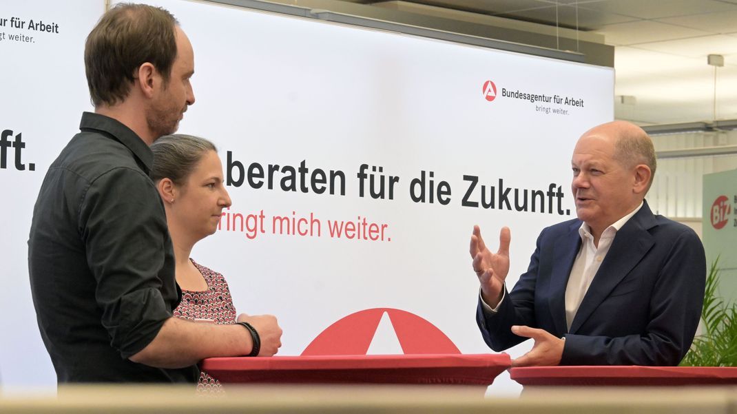 Bundeskanzler Olaf Scholz (r) spricht mit Christian Klauß (l) und Franziska Reinhold, beide Mitarbeiter der Arbeitsagentur.