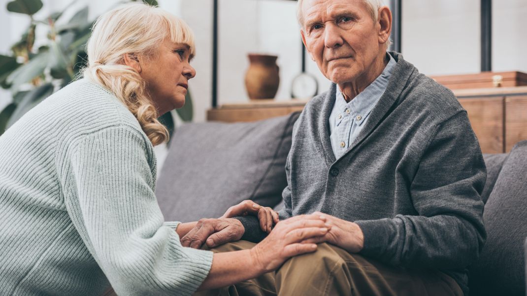 retired wife looking at senior husband in living room