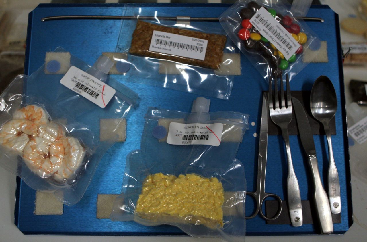 Im Johnson Space Center in Houston wurde 2005 ein typisches Astro-Essen ausgestellt. Sehr beliebt: der Shrimp Cocktail. Die Tütchen sind mit Klettband befestigt, das Besteck bleibt dank Magneten an Ort und Stelle. 