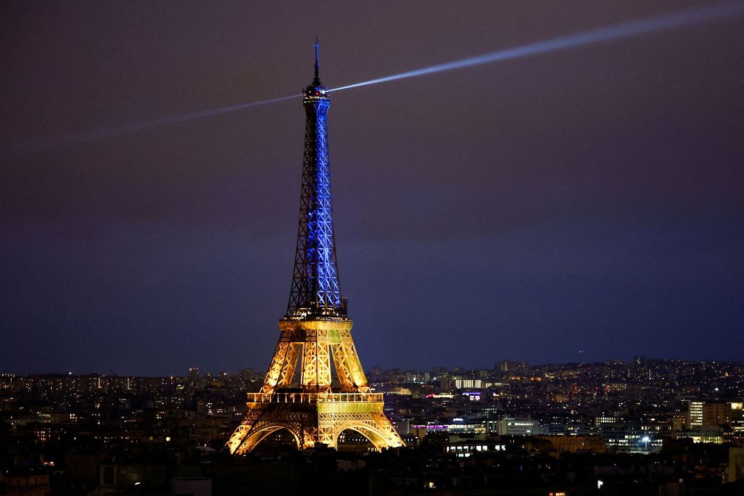 Der Eiffelturm in Paris strahlt in blau-gelb.