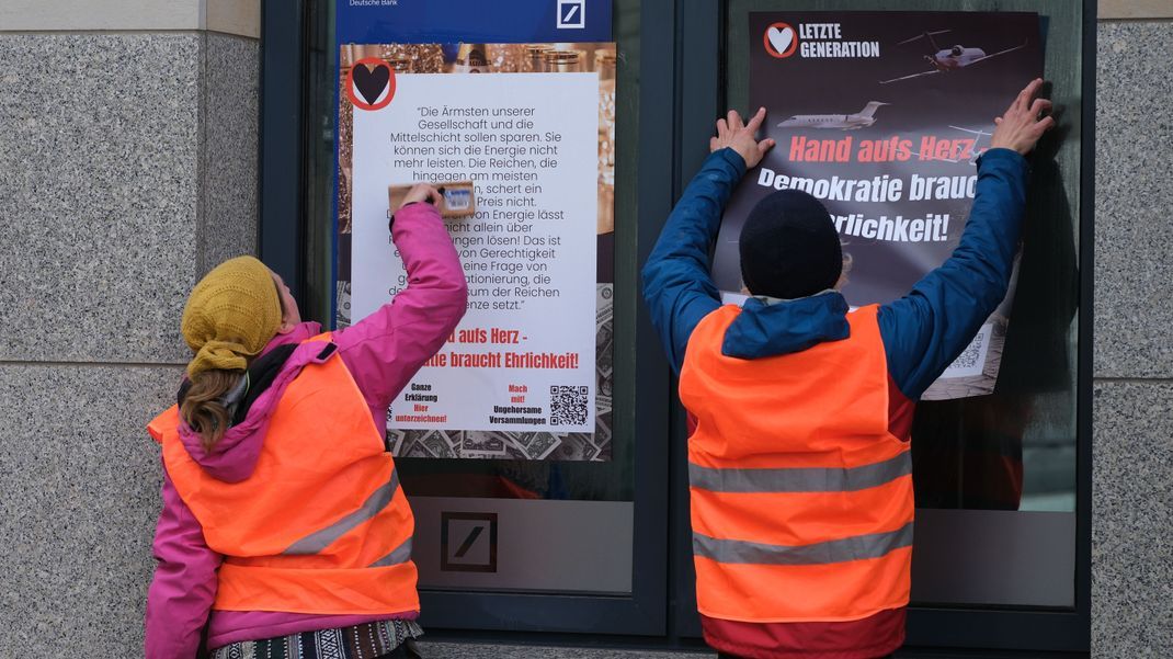 Aktivist:innen der Klimabewegung Letzte Generation kleben Ende April Plakate auf die Schaufenster einer Filiale der Deutschen Bank in Leipzig. Solche Protestaktionen machten die Gruppe landesweit bekannt.