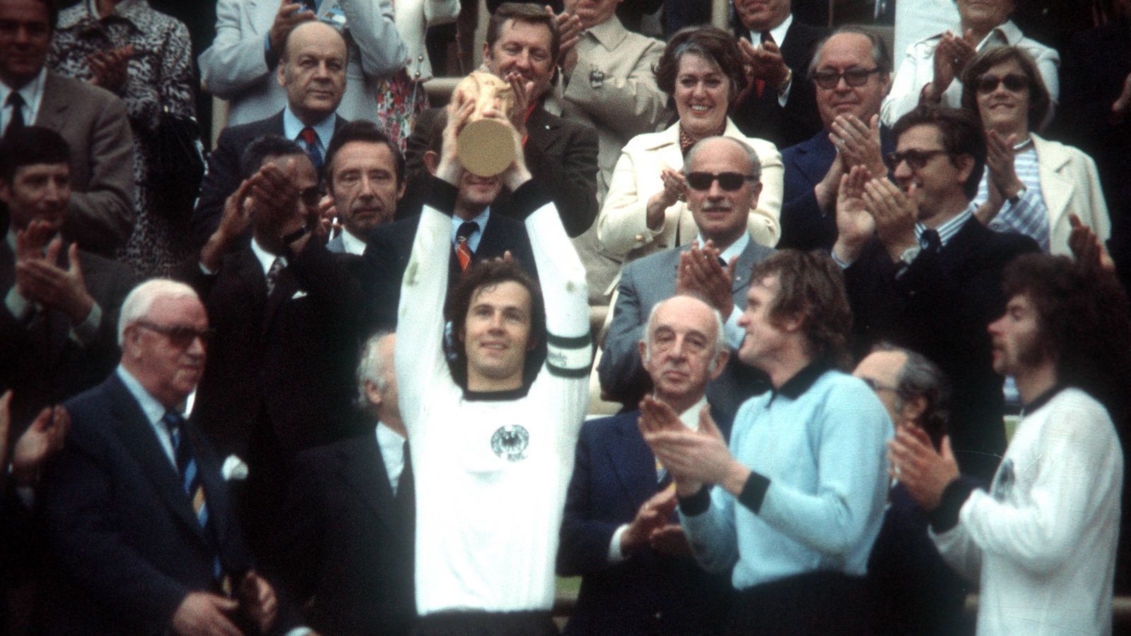 
                <strong>WM 1974 - Deutschland</strong><br>
                Franz Beckenbauer hebt die Trophäe in den Himmel. Im Finale gegen die Niederlande schießt Gerd Müller das Siegtor zum 2:1 und Deutschland gewinnt zum zweiten Mal nach 1954 die Weltmeisterschaft. Damit ist die deutsche Elf der erste amtierende Europameister, der auch Weltmeister werden konnte. Einzig der spanischen Nationalmannschaft gelang mit ihrem Triumph bei der WM 2010 diese Leistung zu wiederholen.
              