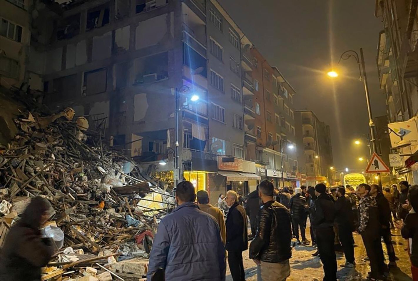 Türkei, Pazarcik: Menschen versammeln sich um ein eingestürztes Gebäude in Pazarcik in der südtürkischen Provinz Kahramanmaras. 