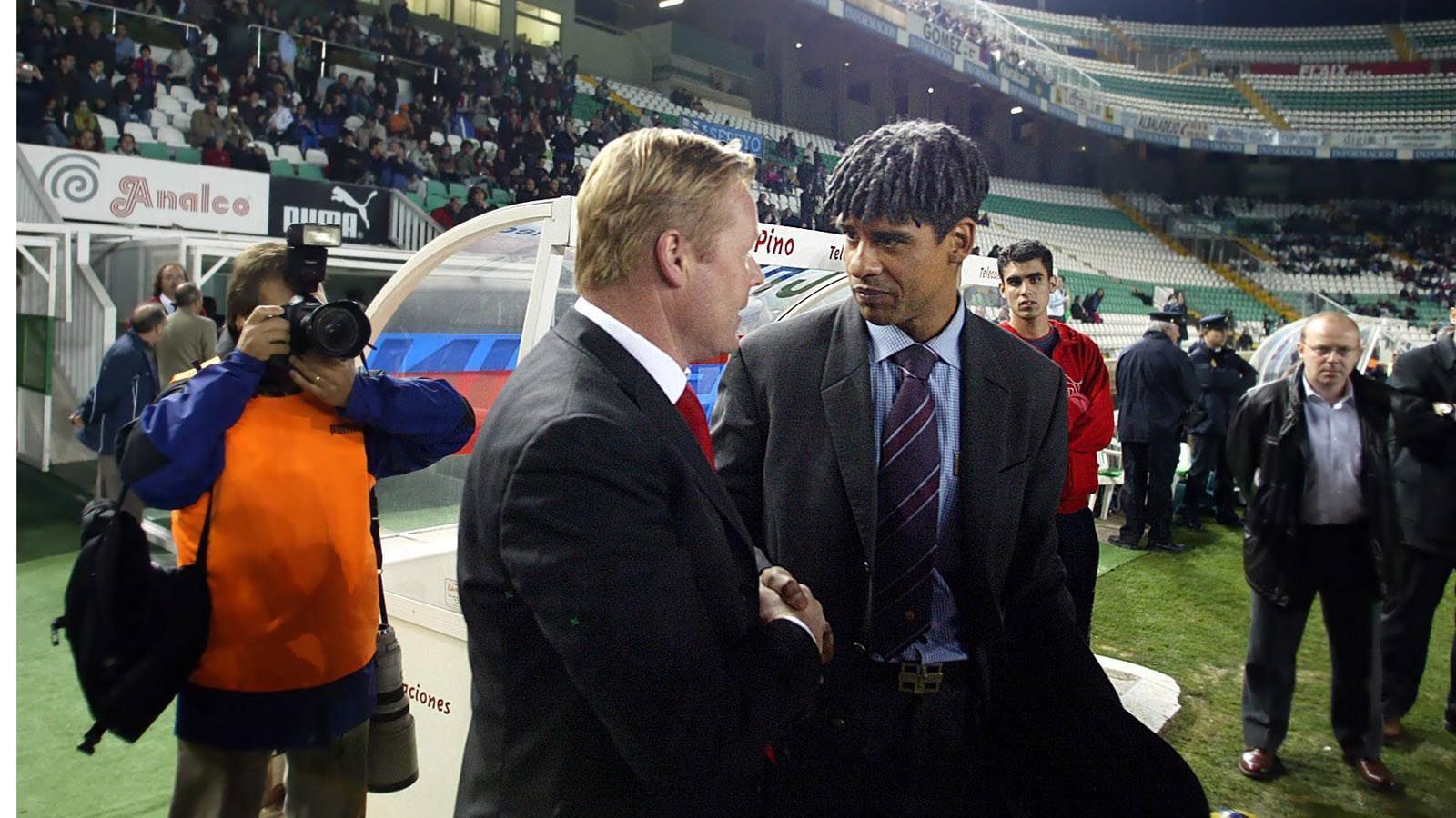 
                <strong>Frank Rijkaard ist Barca-Coach</strong><br>
                Der Niederländer Frank Rijkaard (r.) führt Barca im Jahr 2004/2005 ins Achtelfinale der Champions League und zum Meistertitel in La Liga. Der junge Messi ist damals noch hauptsächlich für die Zweite Mannschaft am Ball, kommt aber bereits auf neun Liga-Einsätze im Profi-Team. Erst in der Folgesaison wird er aber voll in die A-Mannschaft integriert. Der Mann links im Bild ist übrigens der jetzige Barca-Trainer Ronald Koeman, damals Coach von Ajax Amsterdam.
              