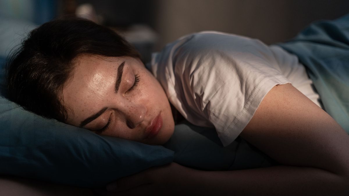 Portrait of beautiful young woman sleeping cozily on a bed in her bedroom at night.