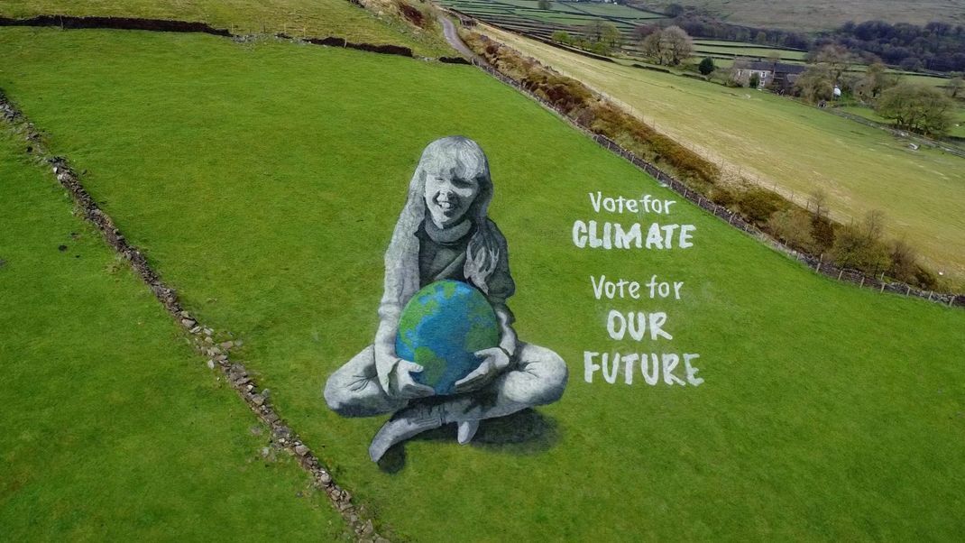 Earth Day 2024: Das 50 Meter große anamorphe Sand-Gemälde wurde von Künstler:innen von Sand In Your Eye innerhalb von drei Tagen erstellt. Es zeigt ein Mädchen, das die Welt in den Armen hält.