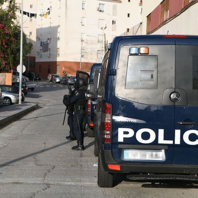 Spanische Polizisten stehen bei einem Einsatzfahrzeug.