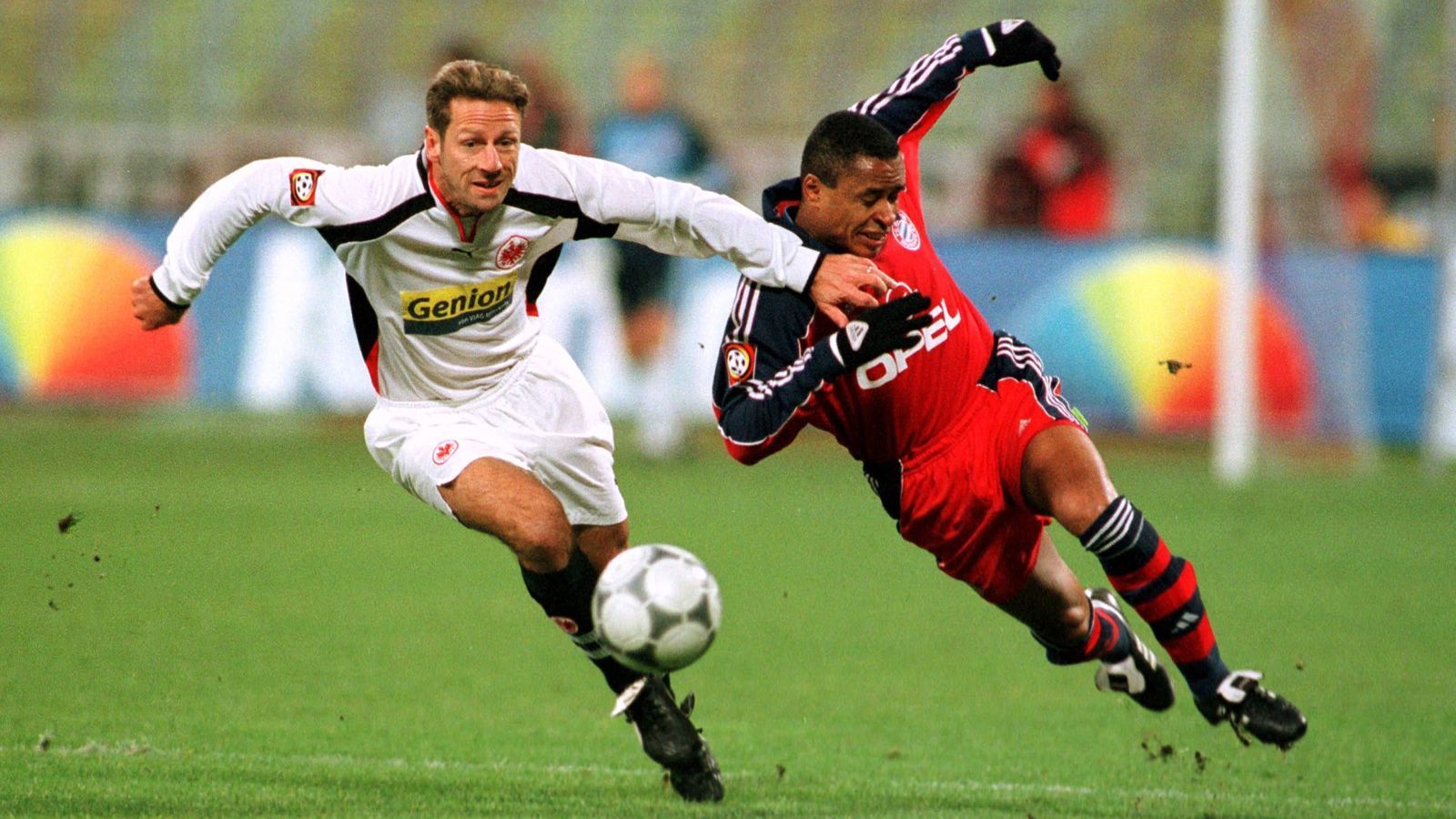 
                <strong>FCB-SGE-2000-Bundesliga</strong><br>
                Bundesliga, 2000/01: Bayern München - Eintracht Frankfurt 1:2 - Fjörtofts SiegtorDer letzte Sieg der Frankfurter in München. Die Bayern kamen schwer in die Saison und kassierten gegen die Eintracht am 13. Spieltag bereits ihre fünfte Saisonniederlage. Nach dem Abpfiff trennten beide Clubs nur zwei Punkte. Am Saisonende waren es 28. Die Bayern feierten die Last-Minute-Meisterschaft von Hamburg, die Hessen stiegen sogar noch ab. An diesem 18. November des Jahres 2000 aber gewann die von Felix Magath trainierte Eintracht (im Bild Uwe Bindewald, li. mit Paulo Sergio) verdient im Olympiastadion. Das Siegtor gelang Jan-Age Fjörtoft nach 63 Minuten. 
              