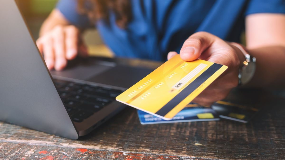 People holding and giving a credit card to someone while using laptop computer