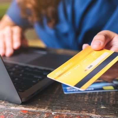 People holding and giving a credit card to someone while using laptop computer