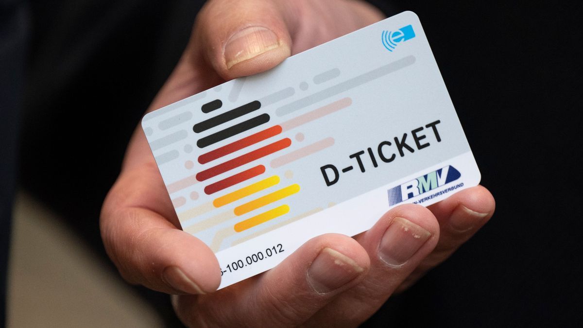 Eine Hand hält ein Deutschlandticket.