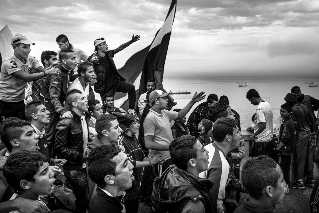 Fußballfans versammeln sich auf der Straße und singen während eines Spiels, das aufgrund von Gewalt hinter verschlossenen Toren stattfindet.