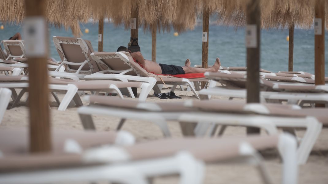 Urlauber entspannen am Strand von Magaluf auf Mallorca.