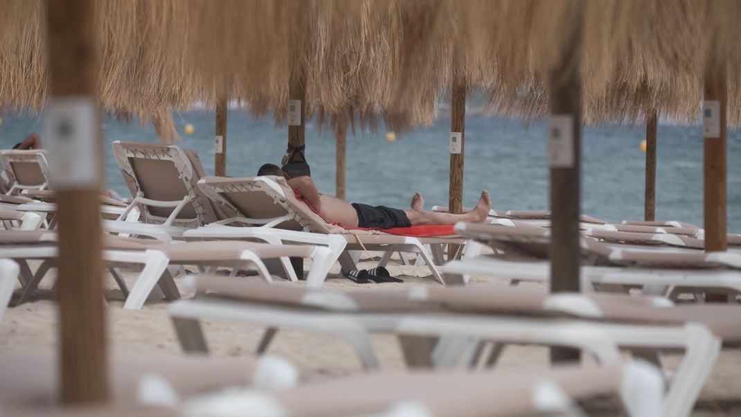 Urlauber entspannen am Strand von Magaluf auf Mallorca.