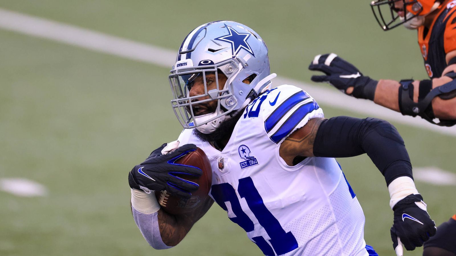 
                <strong>Was macht Ezekiel Elliott?</strong><br>
                Auf ihn werden ebenfalls viele Augen gerichtet sein. Der Running Back trat 2020 den Beweis an, dass er vor allem an der Seite von Prescott brilliert. Die vergangene Saison war seine statistisch schlechteste, denn er trug den Ball im Schnitt nur über vier Yards, kam insgesamt auf 979 Yards und blieb damit erstmals unter der magischen Marke von 1.000 Yards bei mehr als elf Spielen. Sechs Touchdowns sind auch nur wenig überzeugend. Auch für ihn gilt: Er muss zulegen.
              