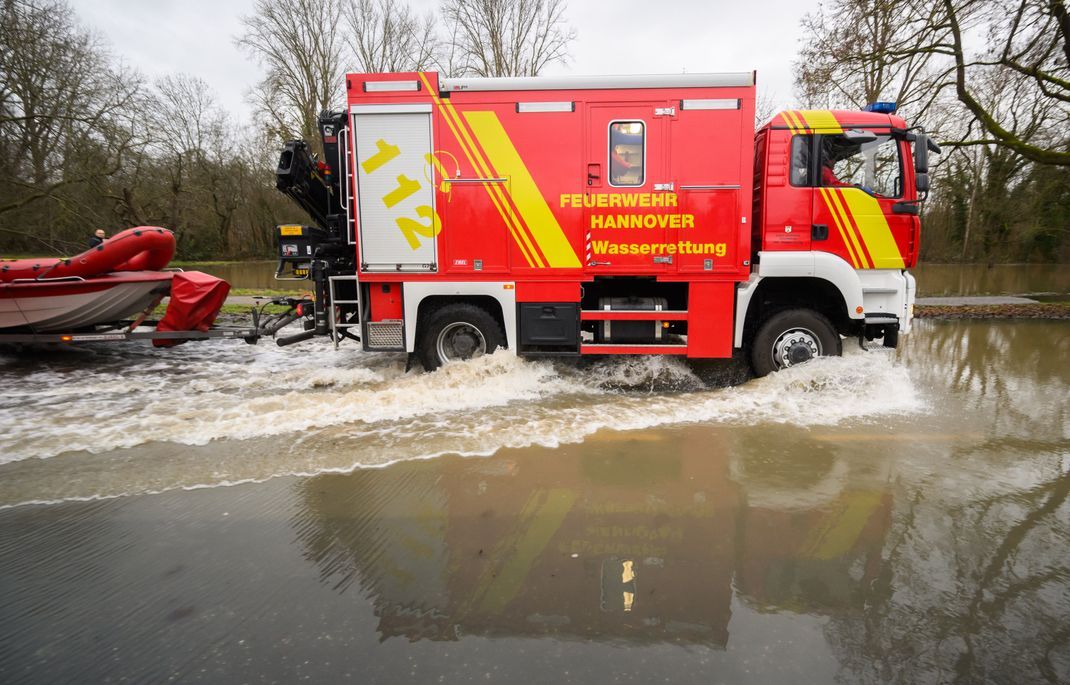 Einsatzkräfte der Wasserrettung der Feuerwehr Hannover fahren über eine überflutete Straße zwischen Hannover und Hemmingen.