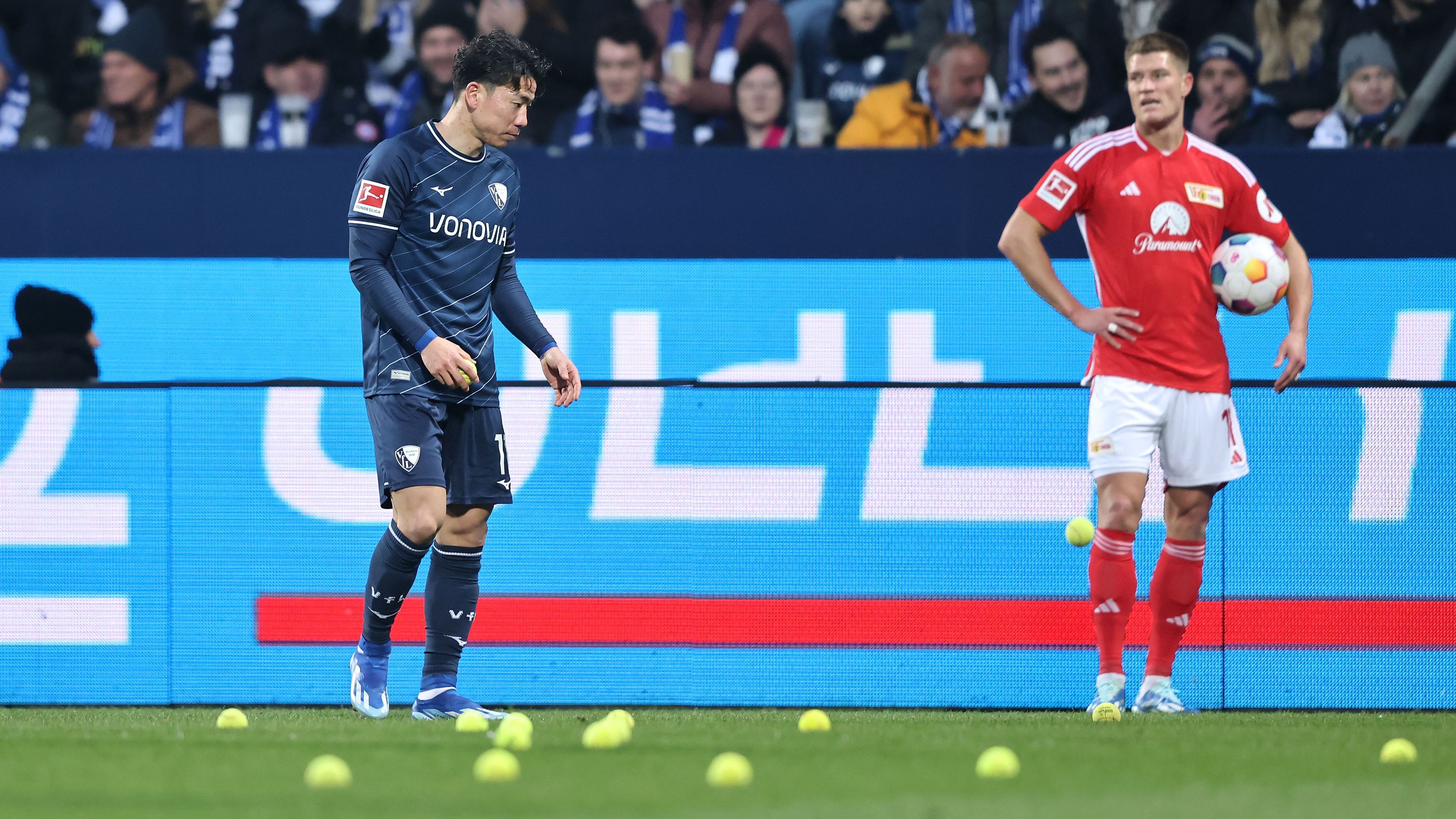 <strong>Schokotaler als Torgarant?</strong><br>Auch in Bochum protestieren die Fans gegen die Investoren-Entscheidung der DFL: Während des Spiels gegen Union Berlin werfen sie zahlreiche Tennisbälle und Schokotaler auf den Platz. Kurios: Bochums Takuma Asano greift zu und isst während der Unterbrechung kurzerhand einen Schokotaler.