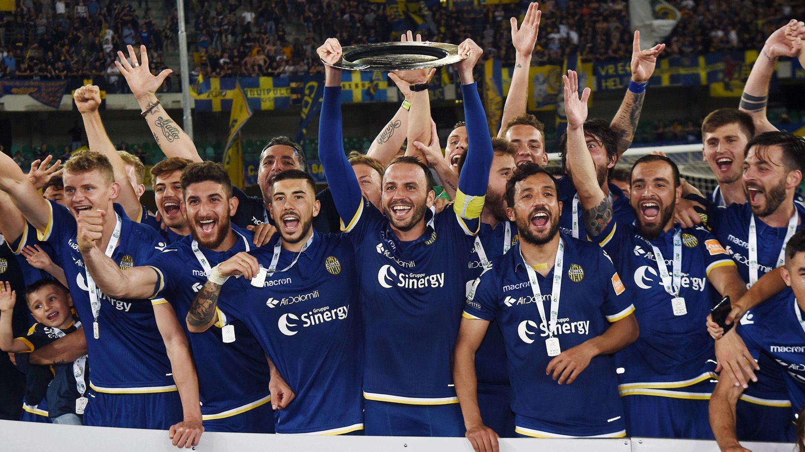 
                <strong>Italien: Hellas Verona</strong><br>
                Hellas Verona ist zurück in Italiens höchster Spielklasse! Nach einer Saison in der Serie B ist Hellas Verona wieder in die Serie A aufgestiegen. Im Final-Rückspiel in der Aufstiegsrunde besiegten die Norditaliener die AS Cittadella 3:0 und drehten damit die 0:2-Niederlage aus dem Hinspiel. In der jüngeren Vergangenheit schaffte es der ehemalige Klub von Thomas Berthold, Luca Toni und Hans-Peter Briegel kaum, mehrere Jahre am Stück in derselben Liga zu spielen. 2011 stieg Hellas in die Serie B ab, 2013 wieder in die erste Liga auf. Nach der dritten Saison ging es zurück in die Serie B. Danach folgten Wiederaufstieg, Abstieg und erneut der Aufstieg.
              