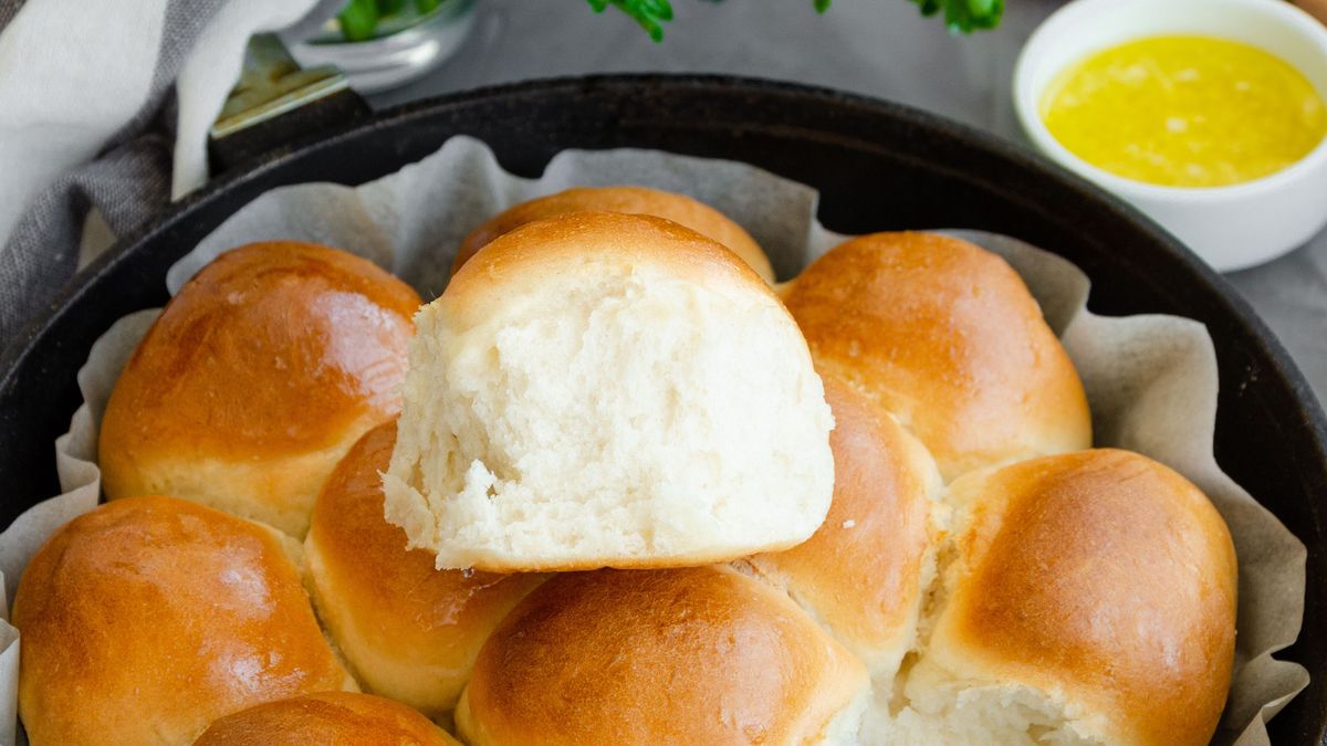 Traditional Ukrainian garlic bread buns in a cast-iron frying pan on a dark concrete background. Vertical orientation, copy space.