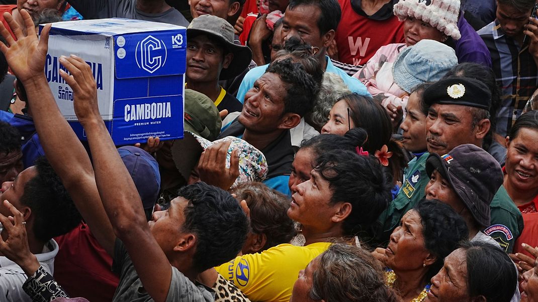 Kambodschaner drängen sich in der Batthkoa-Grundschule in der Provinz Oddar Meanchey, Kambodscha, um Trinkwasser zu erhalten, das von einem lokalen Unternehmen namens Cambodia gespendet wurde. Die Kämpfe an der Grenze zwischen Thailand und Kambodscha gehen in den dritten Tag. 
