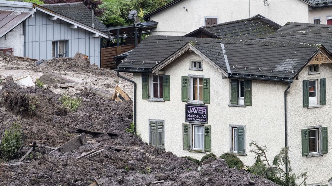 Schweiz, Schwanden: Geröll und Schlammmassen umgeben Häuser nach einem Erdrutsch.