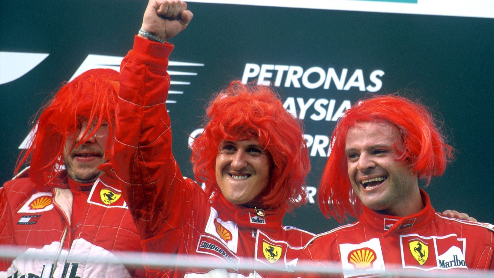
                <strong>WM-Titel Nr. 3 - 2000</strong><br>
                2000 war es dann endlich soweit! Beim GP von Japan in Suzuka auf einer von Schumachers Lieblingsstrecken machte der damals 31-Jährige seinen ersten Titel mit der Scuderia Ferrari perfekt, krönte sich insgesamt zum dritten Mal als Champion. Ein emotionaler Moment, der auch in Deutschland und Italien ausgiebig zelebriert wurde. Auf die Welle der roten "Schumania" hin reagierte auch Ferrari und feierte zum Saisonfinale in Malaysia mit roten Perücken ihren Weltmeister.
              