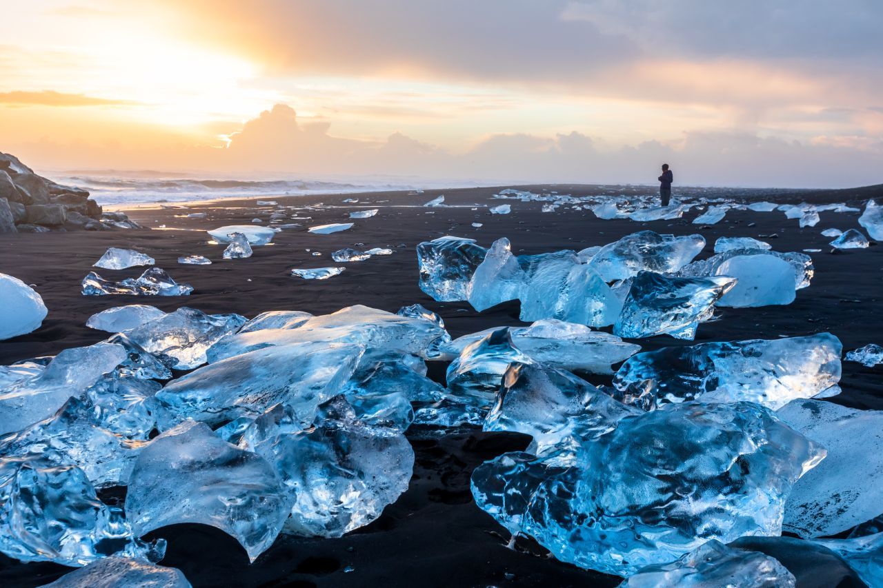 Blau schimmerndes Gletscher-Eis auf pechschwarzem Vulkan-Sand, dieses Schauspiel findest du am "Diamont Beach" auf Island. Beim Schmelzen des Gletschers werden im Sommer Eisbrocken über einen Zufluss ins Meer gespült und an den Strand geschwemmt. Dort wirken sie tatsächlich wie glitzernde Diamanten.