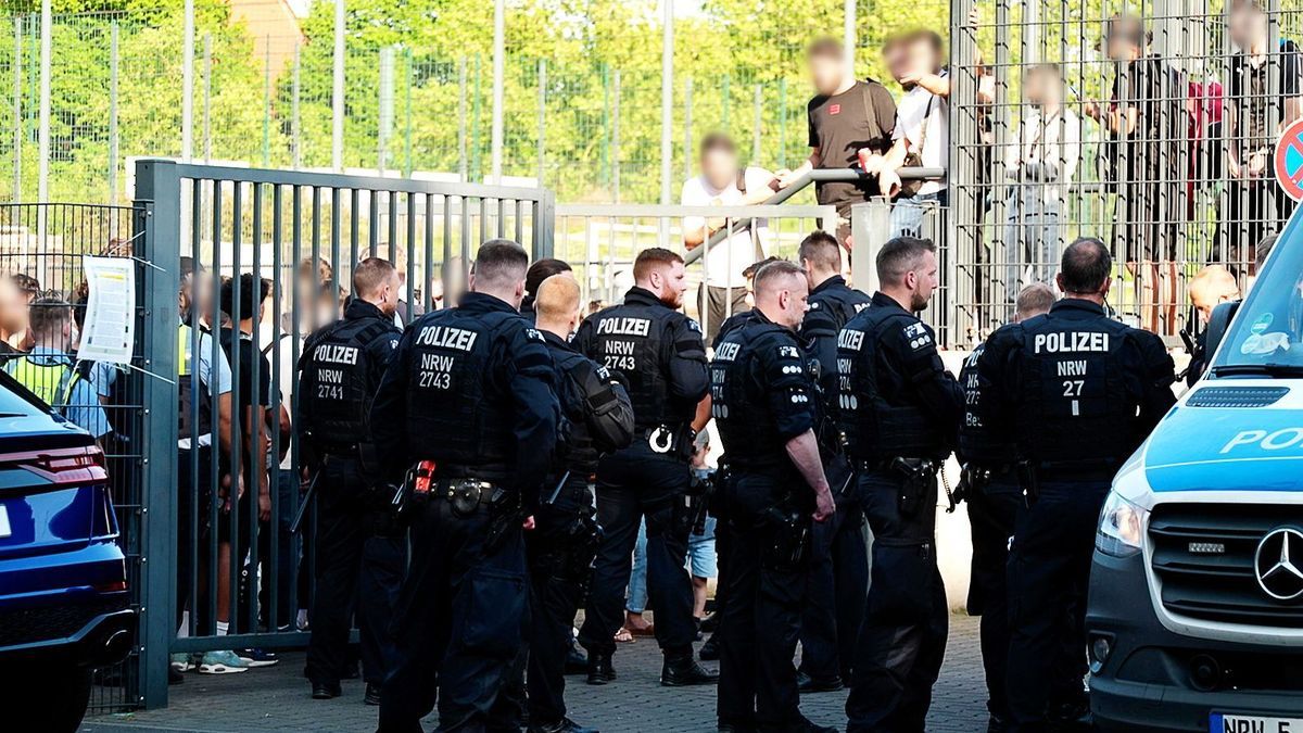 Einsatzkräfte der Polizei stehen vor der Bezirkssportanlage Bäuminghausstraße. 