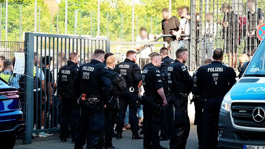 Einsatzkräfte der Polizei stehen vor der Bezirkssportanlage Bäuminghausstraße.