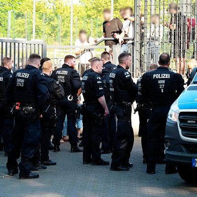 Einsatzkräfte der Polizei stehen vor der Bezirkssportanlage Bäuminghausstraße. 