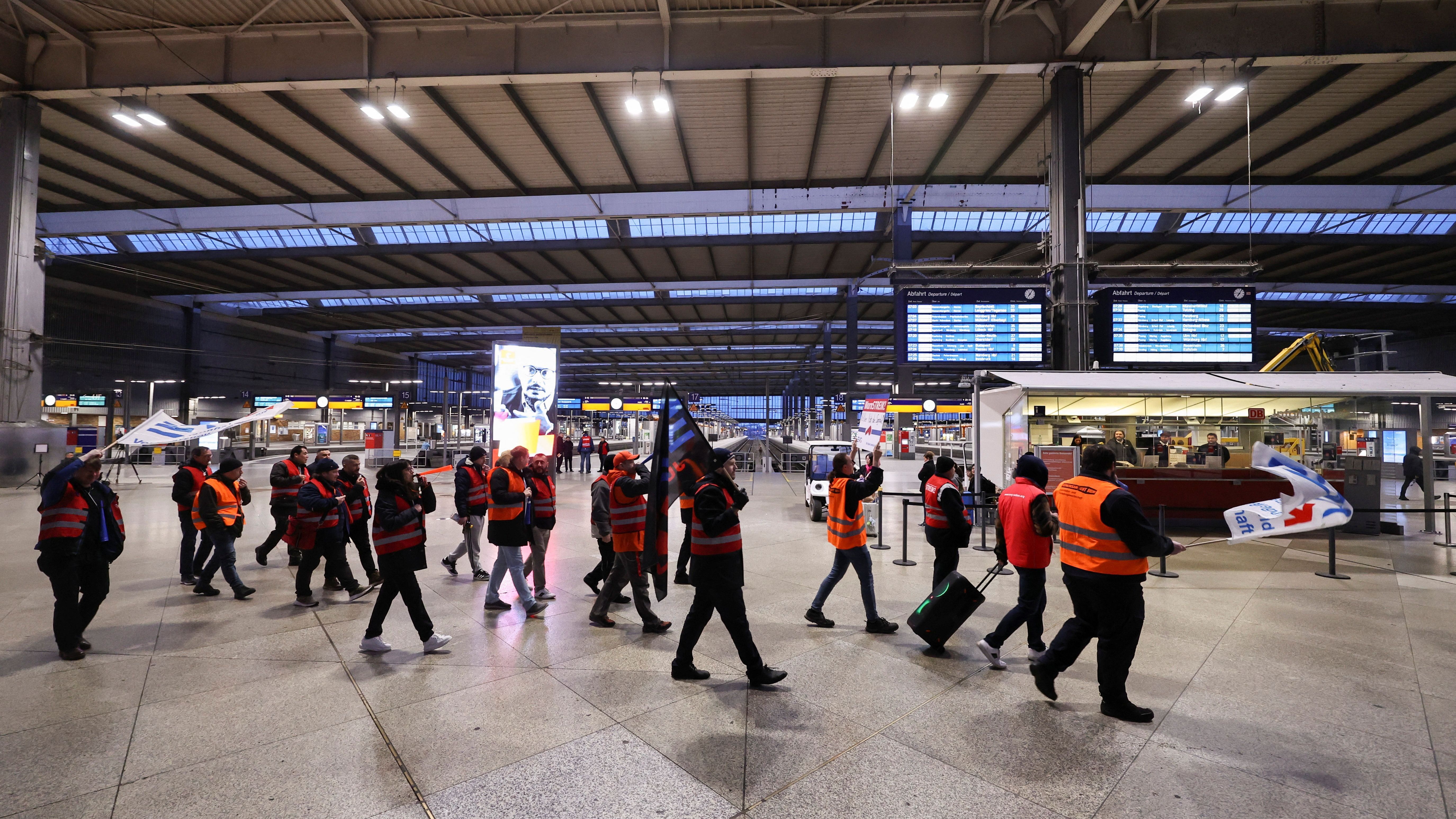 München: Arbeitnehmer:innen protestieren am Münchner Hauptbahnhof, während dieser ansonsten menschenleer ist.