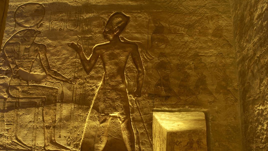 Gott Re wird häufig mit einem Falkenkopf und einer Sonnenscheibe darüber dargestellt. Hier auf einem Thron vor dem Pharao Ramses II.