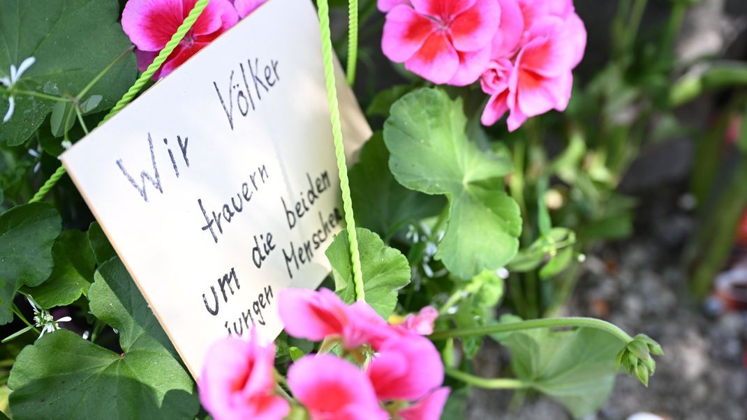 Neben dem Einkaufszentrums an dem am Samstagabend zwei Männer aus der Ukraine getötet worden sind, haben Menschen Blumen und Plakate niedergelegt.