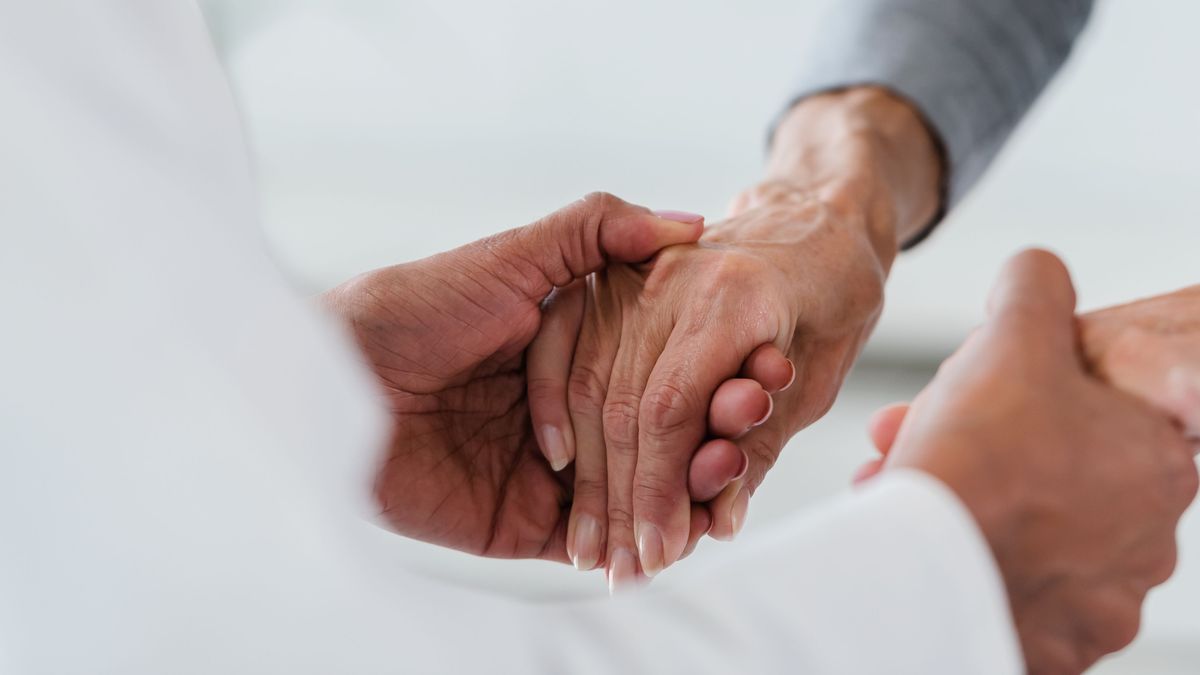 Hands of a doctor holding hands of elderly patient. Checking symptoms of stroke. Medical care and support concept.