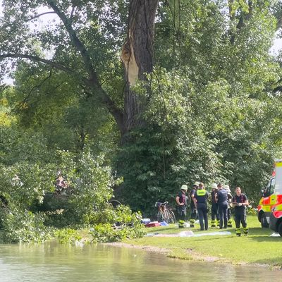 4. August 2024, München: Rettungskräfte stehen an der Unglücksstelle im Englischen Garten in München, an der ein großer Ast abbrach, auf zwei Menschen fiel und diese verletzte. 