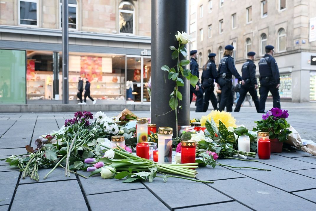 Kerzen und Blumen liegen in der Nähe des Paradeplatzes in Mannheim an einer Straßenbahnhaltestelle. (Archivfoto)