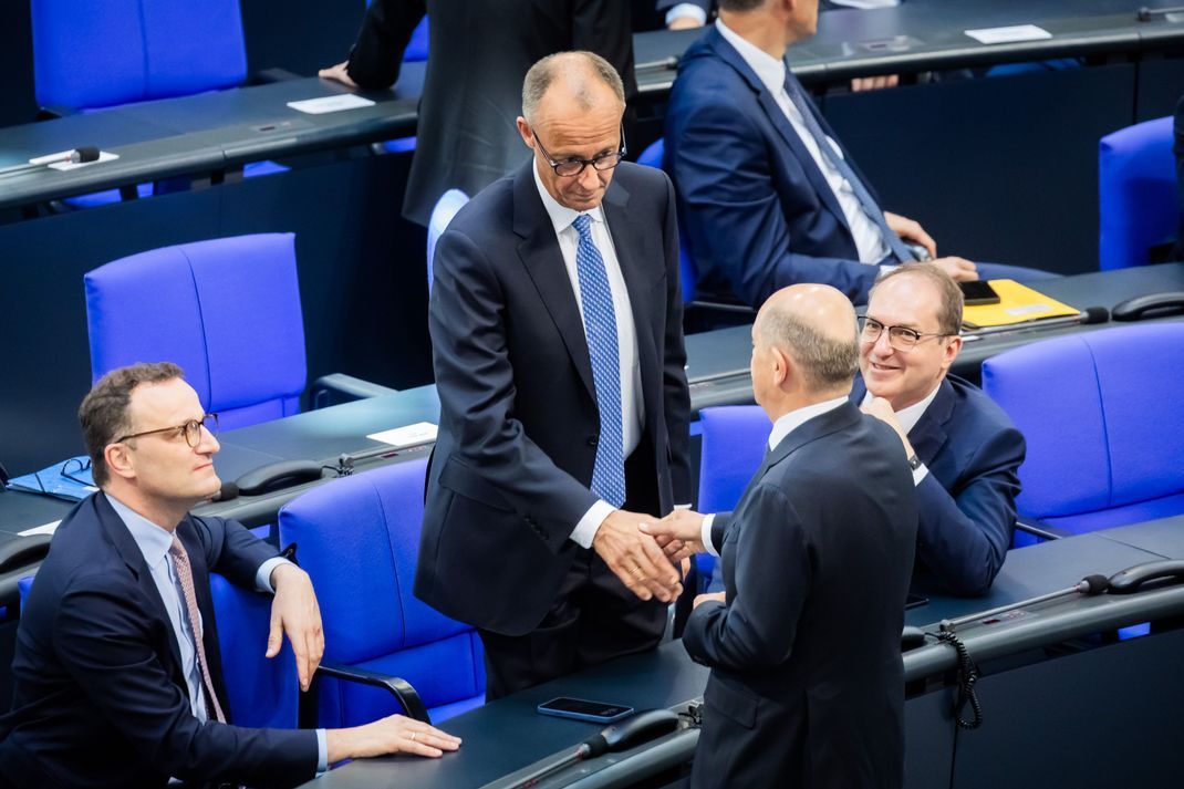 Der designierte Bundeskanzler Friedrich Merz (CDU, Mitte oben) und der geschäftsführende Bundeskanzler Olaf Scholz (SPD, unten Mitte) schütteln sich neben Jens Spahn (CDU, links) und Alexander Dobrindt (CSU, rechts) die Hand. 