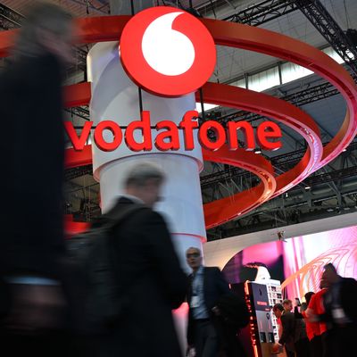 3. März 2025, Spanien, Barcelona: Menschen gehen auf der Mobilfunk-Messe Mobile World Congress (MWC) am Stand des Telekommunikationskonzerns Vodafone vorbe