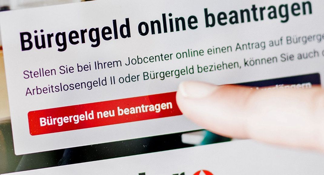 Eine Frau tippt auf einem Tablet auf einen Link zum Beantragen des Bürgergeldes im Kundenbereich im Jobcenter Berlin Mitte.