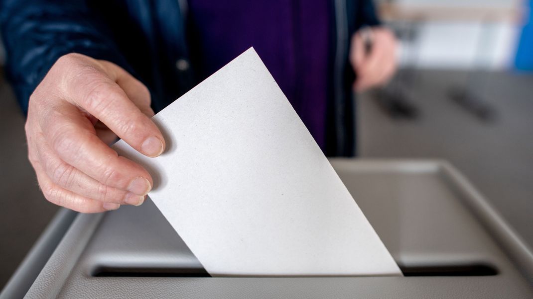 Ein Wähler wirft in einem Wahllokal seinen Stimmzettel für die Bundestagswahl in eine Wahlurne.