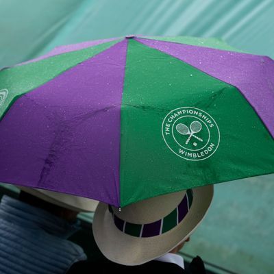 Wimbledon: Menschen schützen sich mit Regenschirmen, nachdem ein Spiel wegen des Regens unterbrochen werden musste. 