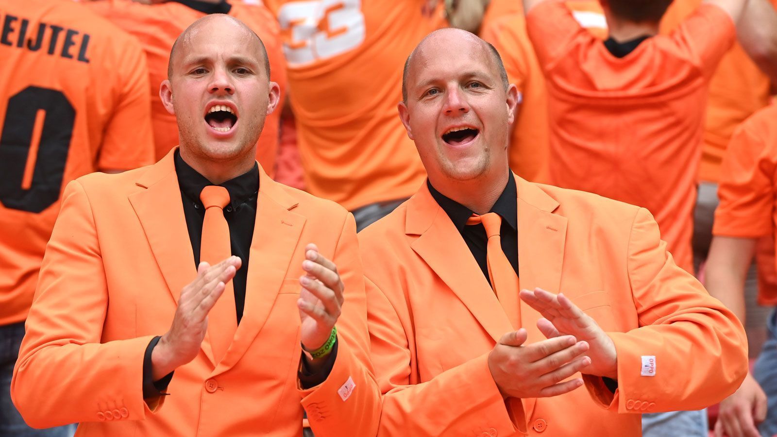 
                <strong>Anzug statt Trikot</strong><br>
                Diese Anhänger haben sich trotz sommerlicher Temperaturen mit 31 Grad Celsius gegen das "Oranje"-Jersey entschieden und laufen heute im Anzug auf.
              