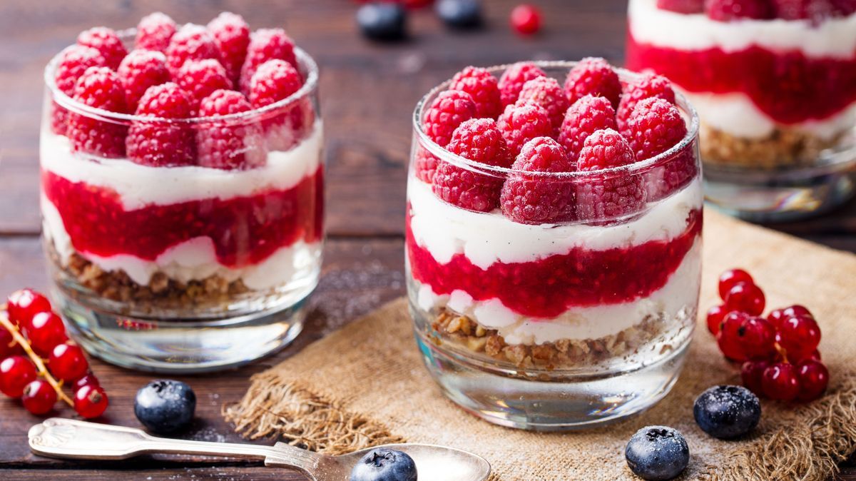 Raspberry dessert, cheesecake, trifle, mouse in a glass on a wooden background