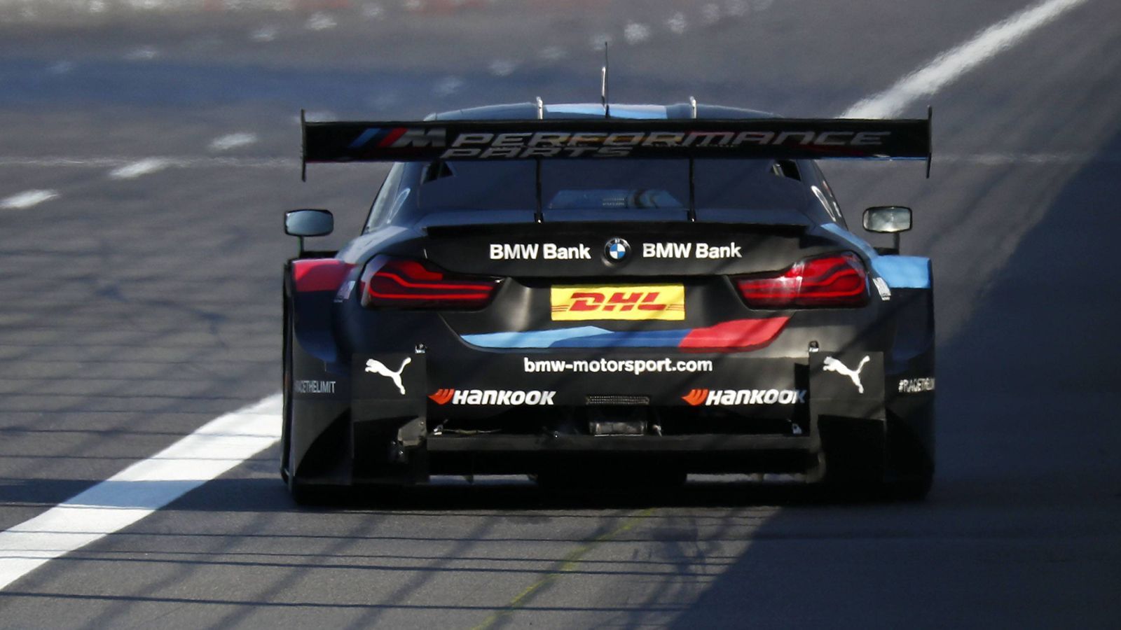 
                <strong>Heckflügel und DRS</strong><br>
                Der Heckflügel der DTM-Autos des Jahrgangs 2019 ist zwar 520 mm breiter als der Vorgänger, verfügt allerdings nur noch über ein Element. In Verbindung mit dem geänderten, nunmehr flacheren Heckdiffusor verringert sich der aerodynamische Abtrieb der Autos. Das DRS ("Drag Reduction System") ist nicht neu. Ein pneumatischer Klappmechanismus des Flügels wird auf Knopfdruck vom Fahrer aktiviert. Die gewünschte Kettenreaktion: Verringerung des Luftwiderstands, Erhöhung des Topspeeds, Verbesserung der Überholmöglichkeit. Eine Neuerung gibt es allerdings beim Modus: Während nach wie vor das DRS nur verwendet werden darf, wenn der Abstand zum Vordermann maximal drei Sekunden beträgt, können die Fahrer ab dieser Saison – außer dem Führenden – in den letzten fünf Runden DRS unabhängig vom Abstand zum Vordermann einsetzen. Im Rennen darf jeder Fahrer das DRS in maximal zwölf Runden aktivieren.
              